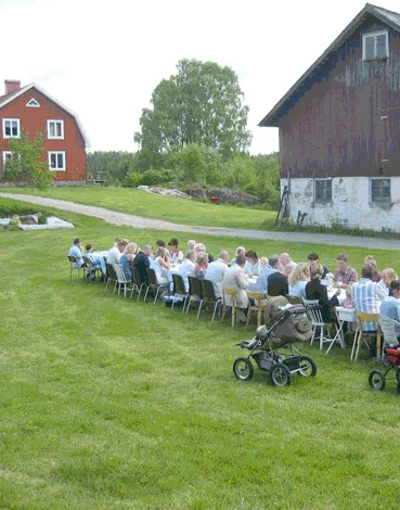 Långbord dukat på gräsmattan med många gäster en sommardag