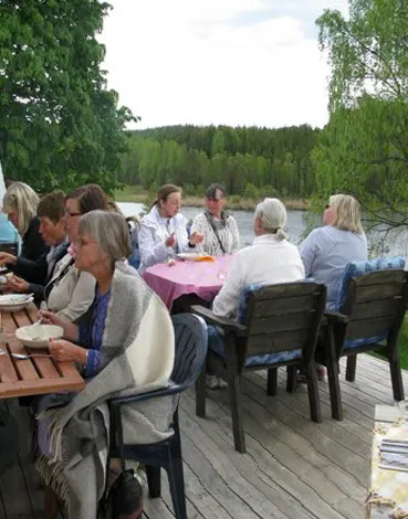 Kursdeltagare som fikar på altanen vid sjön