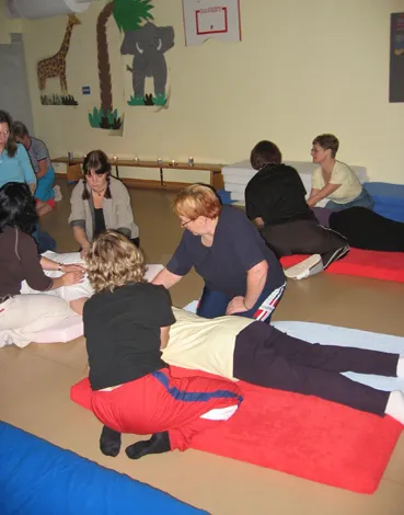 Förskolepersonal övar massage på varandra på mattor under en kurs